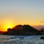 black rock formation on sea during sunset